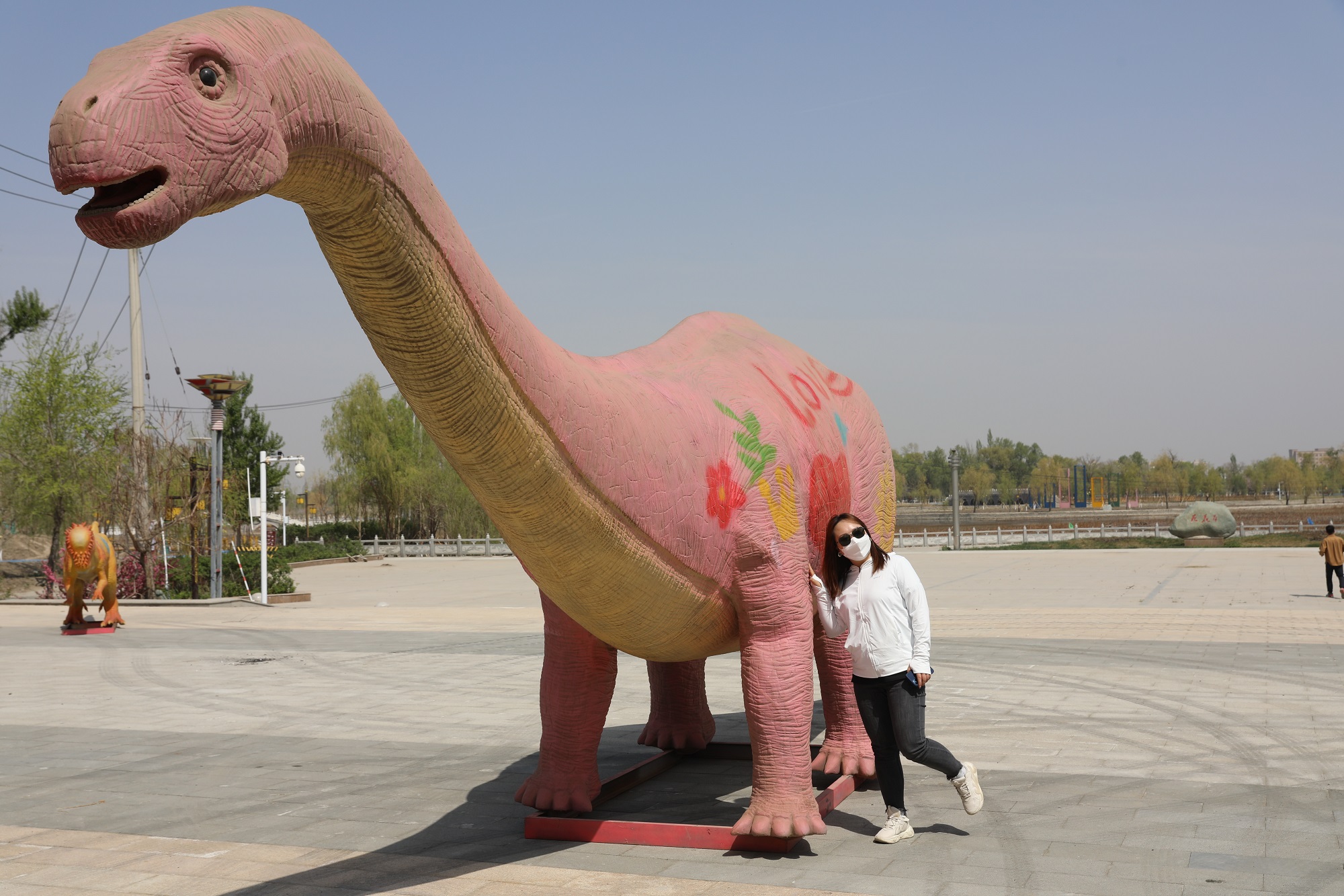 青格达湖景区内游客在与恐龙模型合影。.jpg