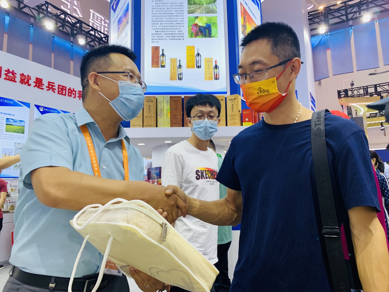 家住海南的王先生（右）慕名来到新疆生产建设兵团展区购买中国彩棉的产品。李萍  摄.png