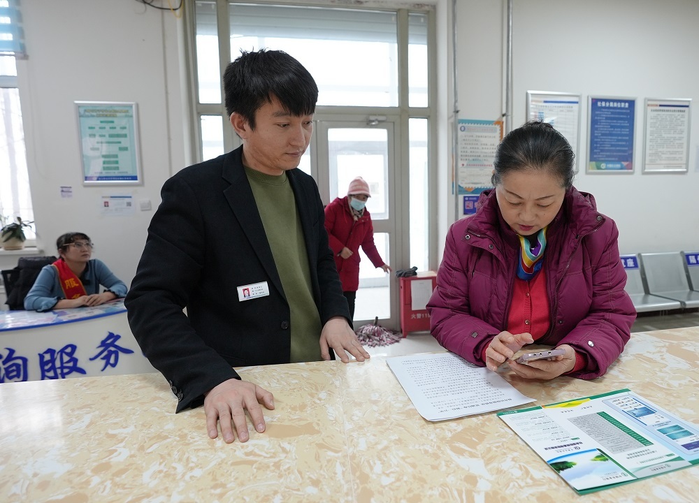1月10日，一五〇团社保分局工作人员桑龙宝（左二）正在指导参保人使用手机办理社保业务。蒲晓霞 摄