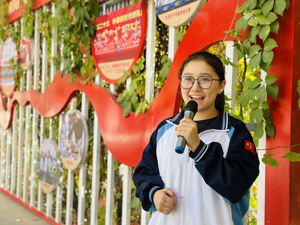 阿拉尔中学八年级学生吐玛热斯·艾尔肯正在为大家讲解阿拉尔中学的校园文化。李萍 摄.png