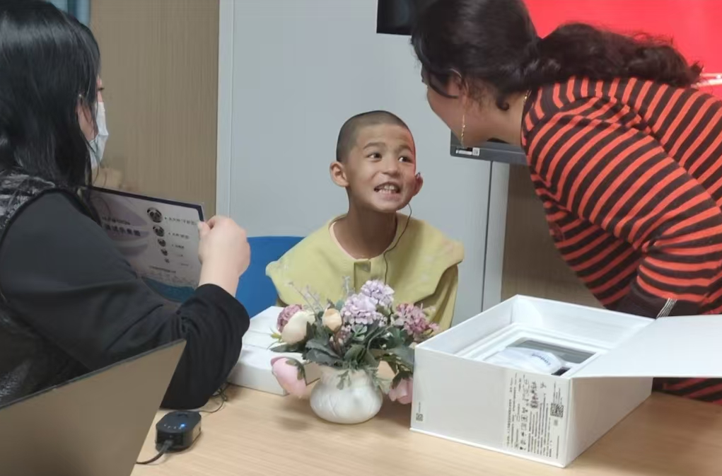 佩戴好人工耳蜗后，患者跟着妈妈学习简单的发音。梁艳摄.png