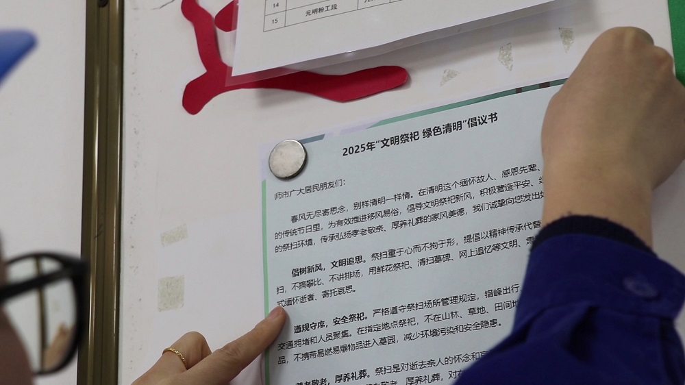 志愿者将倡议书张贴在公告栏上.jpg