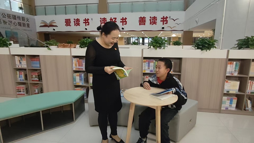 图书馆里，汪迪在给一名看书的小朋友推介图书。梁艳摄.jpg