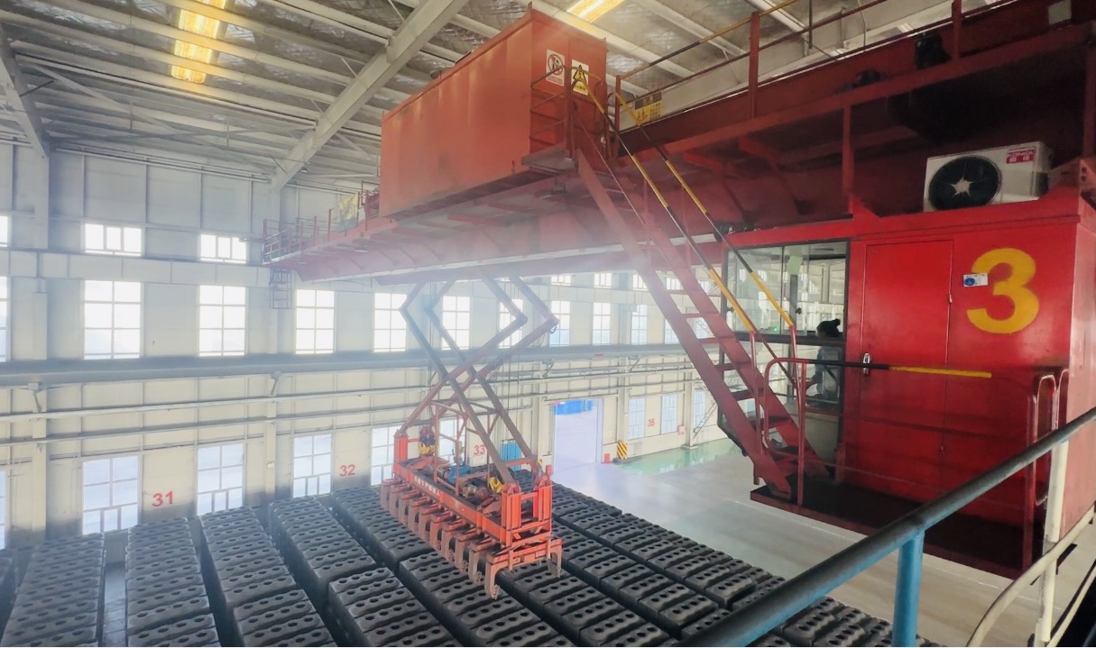 在阿拉尔市南疆碳素新材料有限公司，工人操作天车码放预焙阳极生料块。李萍 摄.png