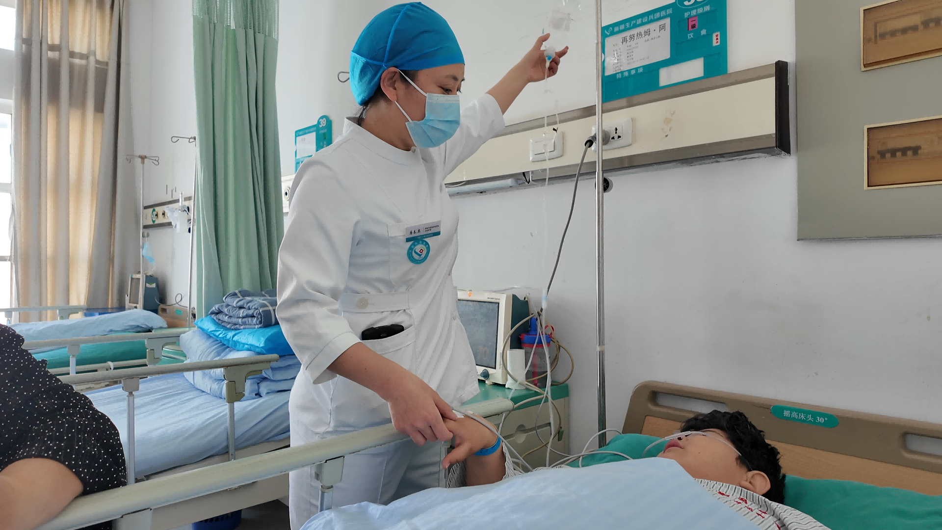 护士正在为患者调整输液装置，时刻关注着患者的身体状况。.png